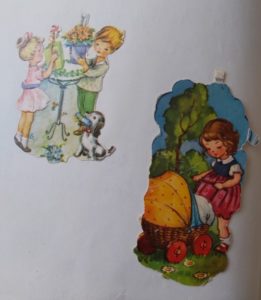 Linke Seite von Inas Eintrag in ein Poesiealbum der 70er Jahre. Es sind zwei Glanzbilder darauf mit jeweils stilisierten Figuren. Auf der einen Darstellung sind Junge udn Mädchen, festlich gekleidet, die auf einem Stehtisch einen Blumenstraß und ein Geschenkpaket abstellen. Das andere zeigt ein kleines Mädchen mit Puppenwagenn